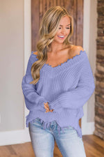 Woman wearing Bella Road frayed hem dropped shoulder sweater in purple, adding quirky fun to her casual outfit.