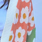 Close-up of a color block open front long sleeve cardigan with floral print and pastel colors in pink, green, and white.