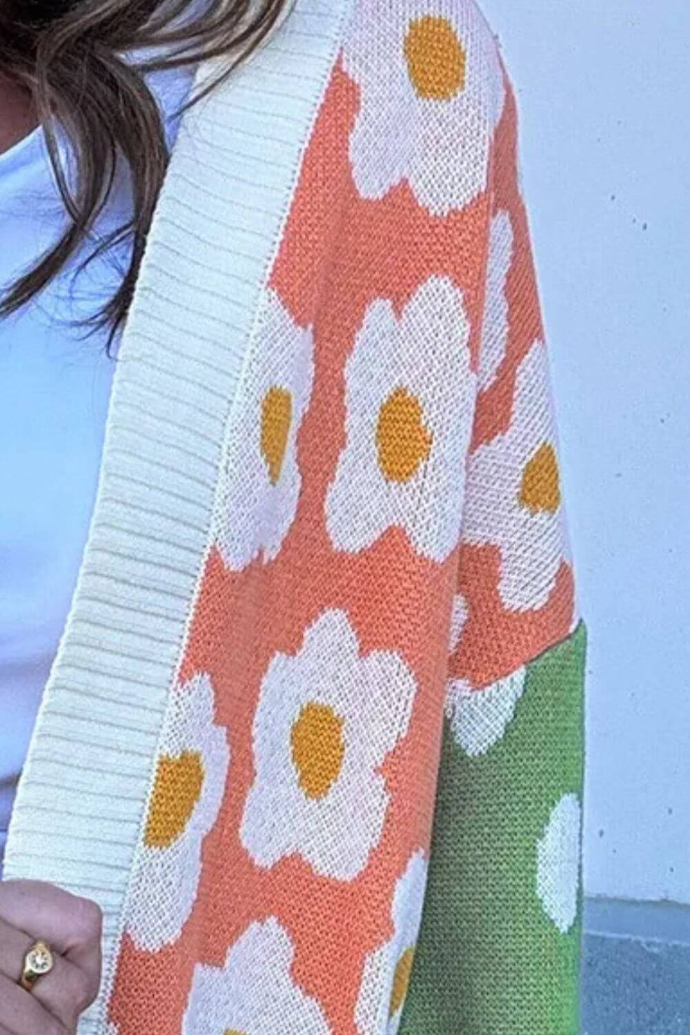 Close-up of a color block open front long sleeve cardigan with floral print and pastel colors in pink, green, and white.