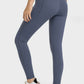 Stylish woman showcasing Millennia V-Waist Yoga Leggings with pockets, rear view in a studio setting.