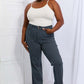 Woman wearing Cassidy Full Size High Waisted Tummy Control Striped Straight Jeans by Judy Blue, posing confidently