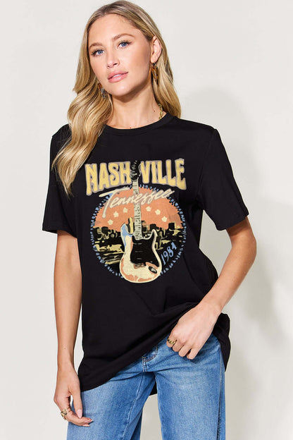 Woman wearing Graphic Round Neck Short Sleeve T-Shirt with Nashville Tennessee guitar print, paired with blue jeans.