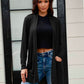 Woman wearing a black open front long sleeve cardigan with pockets, paired with a black top and ripped jeans.