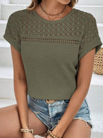 Woman wearing a semi-sheer green waffle-knit round neck short sleeve top with lace detail and denim shorts