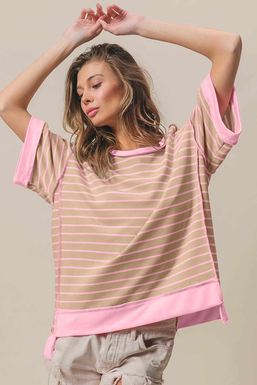 Woman wearing Exposed Seam Stripe Contrast T-Shirt with pink contrasting stripes and seam details, paired with distressed shorts.