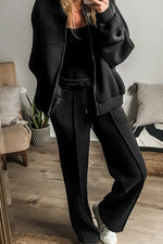 Woman wearing Bella Road zip up long sleeve top and pants set in black, standing in a stylish room