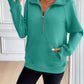 Woman wearing Ivy Lane Half Zip Raglan Sleeve Sweatshirt in green with pocketed front and black shorts.