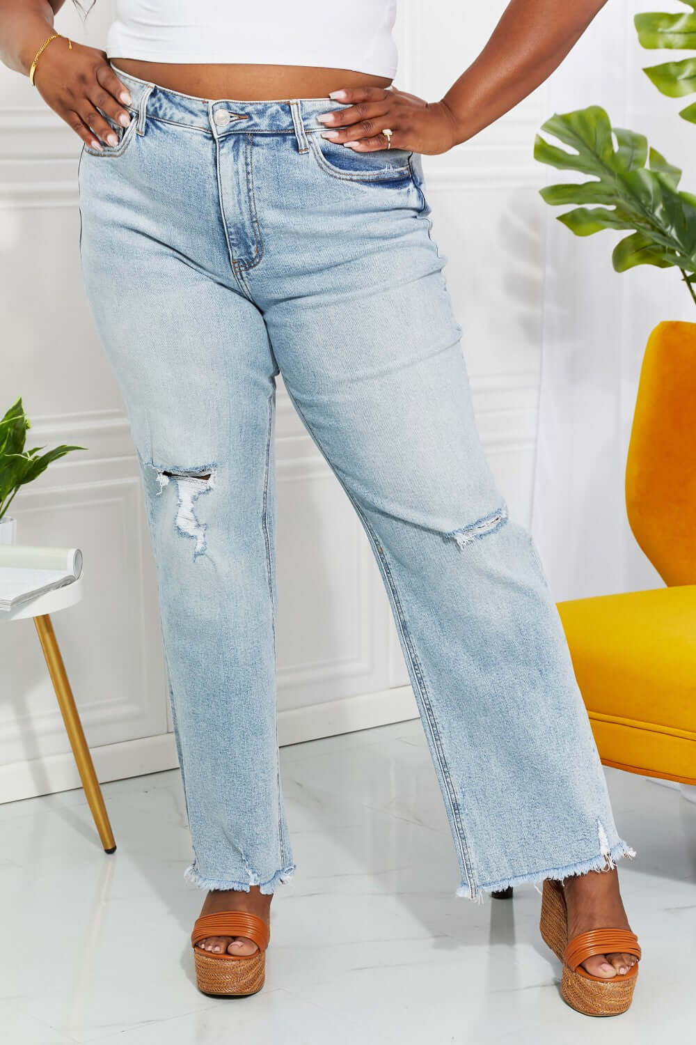 High-waisted Allie 90's Dad Jeans with light wash, distressed details, and raw hem styled with a casual street look.