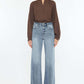 Woman wearing Kancan high-rise slim wide leg jeans in light wash with a brown blouse, showcasing modern style and comfort.