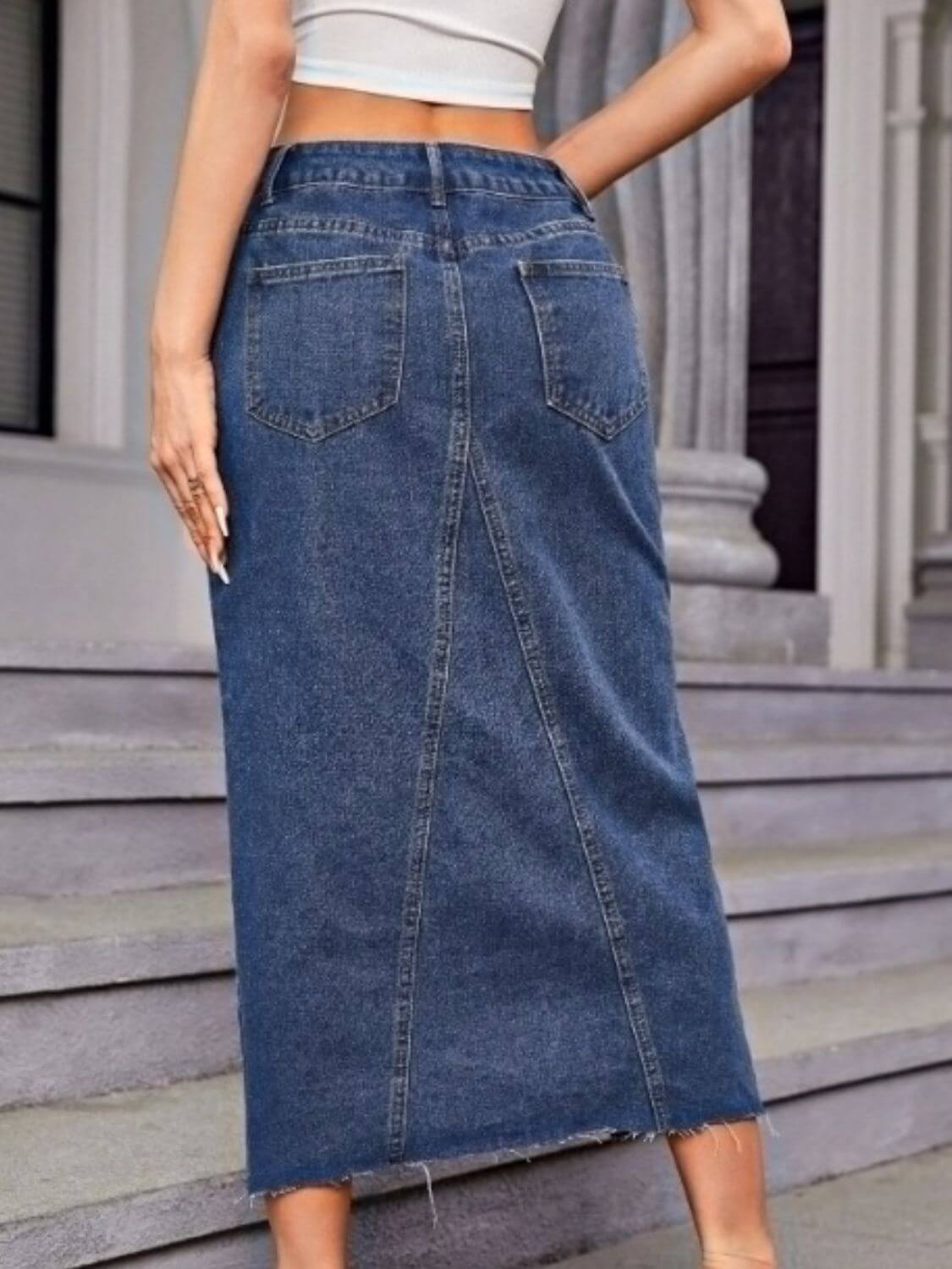 Woman wearing Bella Road Slit Midi Denim Skirt with Pockets, showcasing back slit and pocket design, perfect for a stylish look.