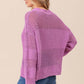 Side view of woman wearing BiBi Openwork Long Sleeve Knit Top in purple, showcasing intricate details, paired with blue jeans.