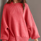 Woman wearing a cozy oversized pink round neck long sleeve sweater with side slits and moderate stretch.