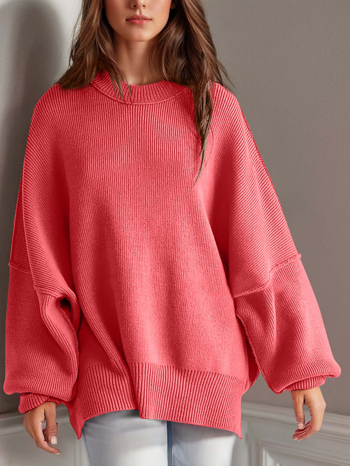 Woman wearing a cozy oversized pink round neck long sleeve sweater with side slits and moderate stretch.