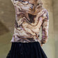 Woman wearing a marble design long sleeve mesh top with elegant swirls and black lace skirt, showcasing contemporary style.