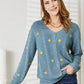 Woman wearing HEYSON full-size blue cable cardigan with yellow floral embroidery, buttoned down and cozy for a stylish layered look.