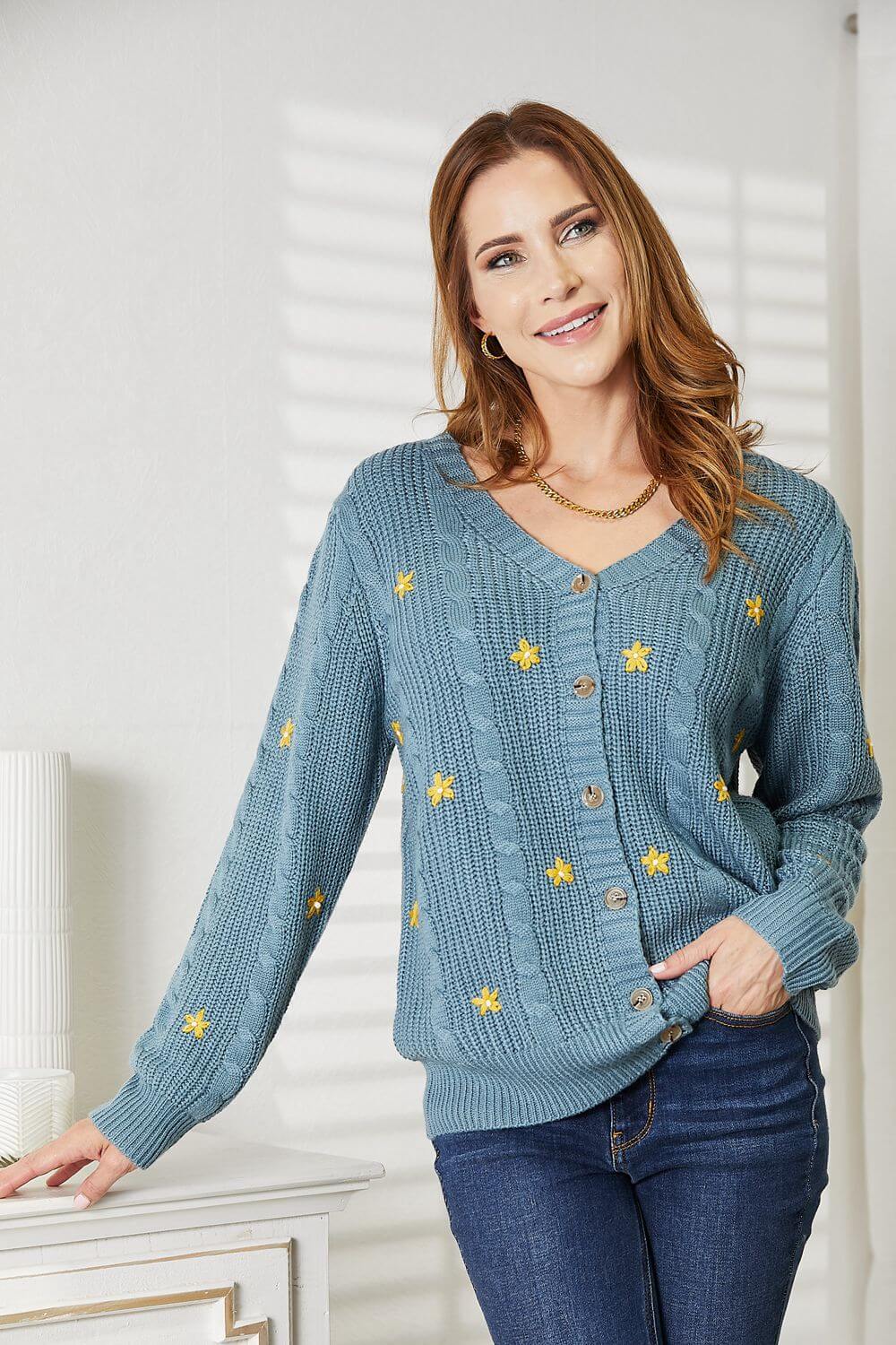 Woman wearing HEYSON full-size blue cable cardigan with yellow floral embroidery, buttoned down and cozy for a stylish layered look.