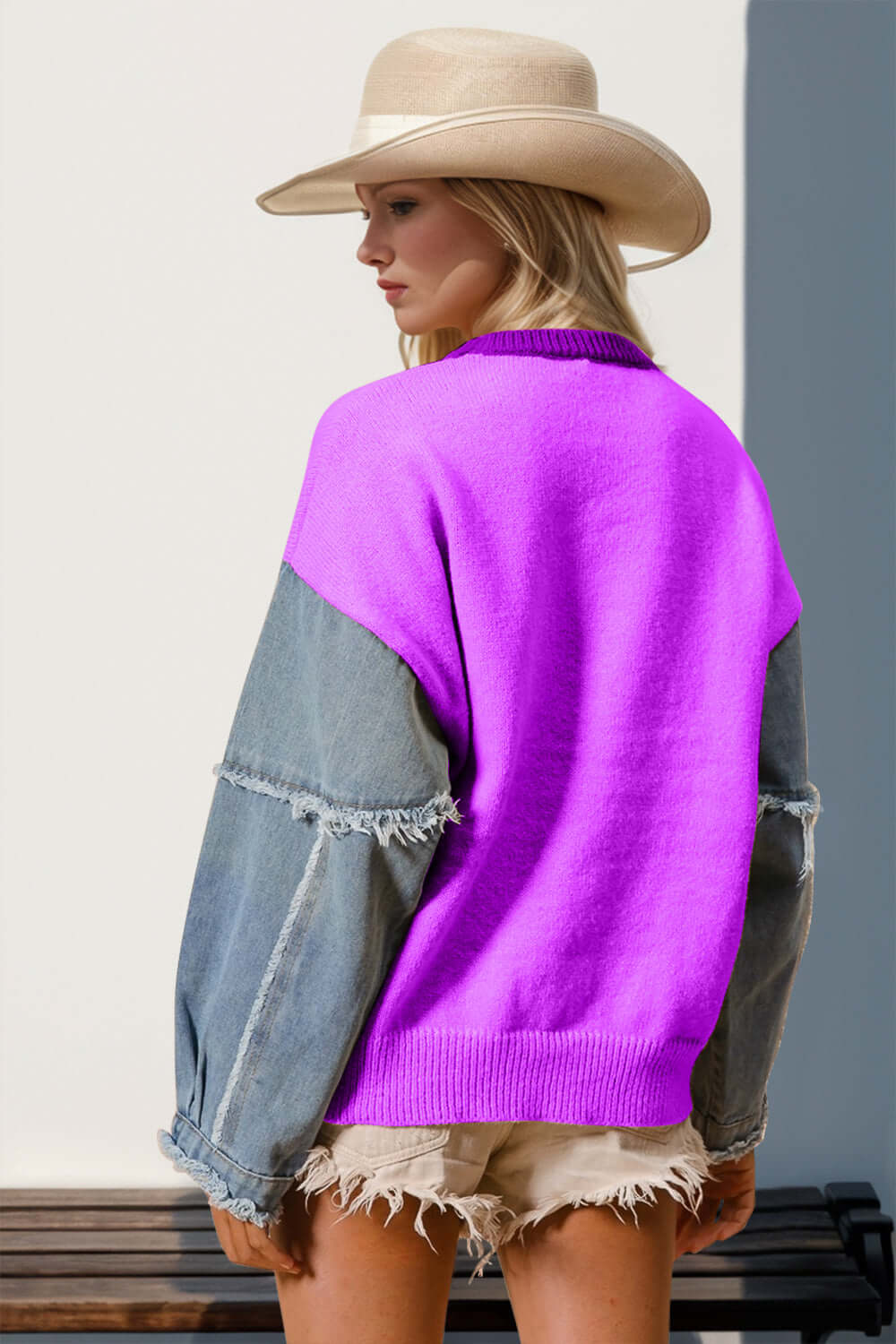 Woman in star pattern sweater with raw edge, wearing a hat and denim shorts, showcasing playful fashion style.