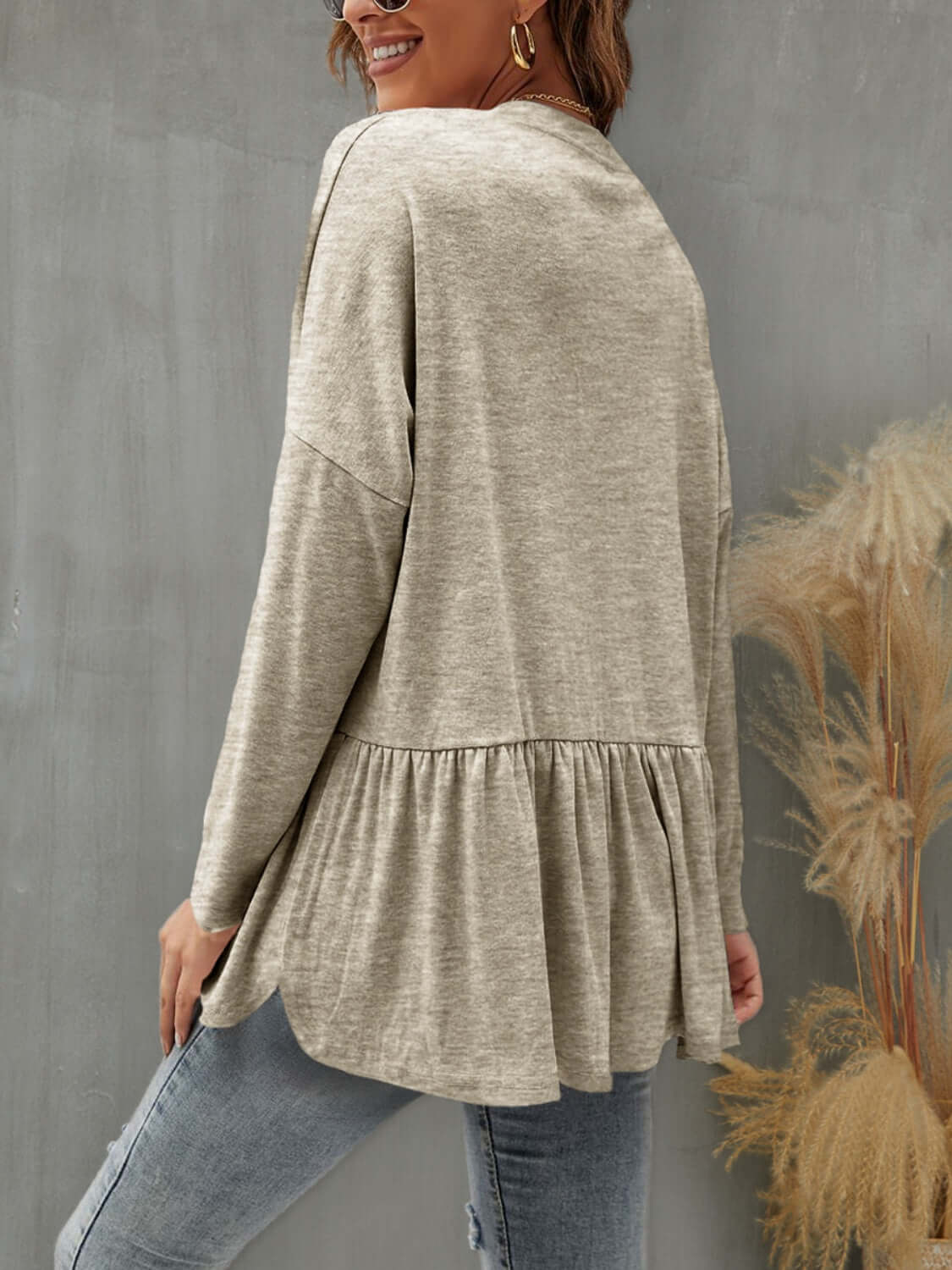 Woman wearing FAM-FAM Ruffled Button Up Long Sleeve Cardigan in khaki, showcasing stylish back ruffles paired with jeans.