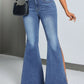 Woman wearing blue slit flare jeans with pockets, paired with a black handbag.