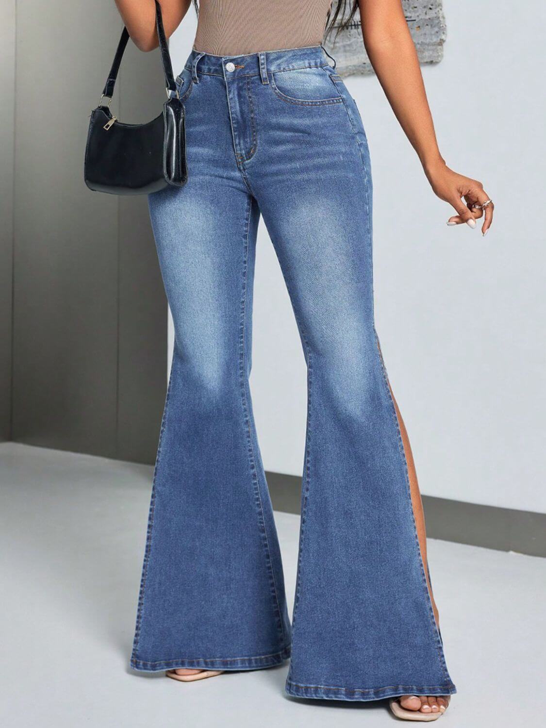 Woman wearing blue slit flare jeans with pockets, paired with a black handbag.