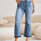 Woman wearing Judy Blue release hem cropped bootcut jeans with ankle strap sandals in a modern living room.