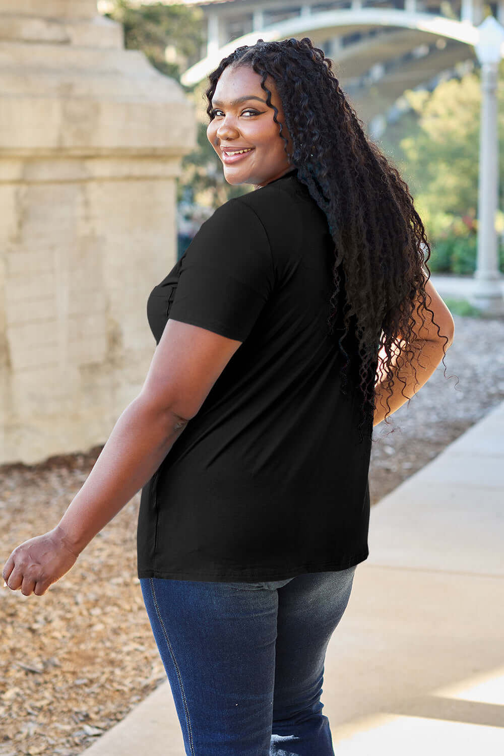 Smiling woman wearing a black Basic Bae Bamboo V-Neck Short Sleeve T-Shirt in casual outdoor setting.