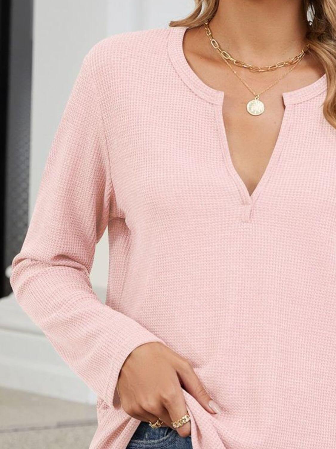 Woman wearing Bella Road waffle-knit notched long sleeve t-shirt in light pink, accessorized with gold necklaces and rings.