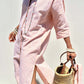 Woman wearing Bella Road Tied Button Up Three-Quarter Sleeve Dress, holding a woven bag, and smiling in the sunlight