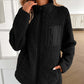 Woman wearing Ivy Lane black fuzzy jacket with zip up front and pocket, perfect for chilly days and cozy style.