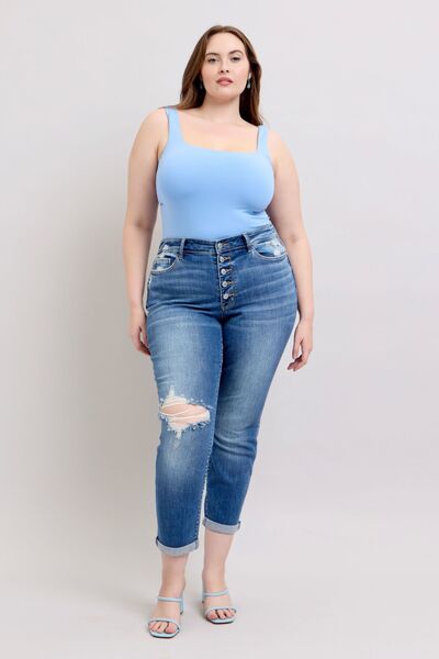 Model in blue bodysuit showcasing Judy Blue plus size button fly distressed jeans with pockets.