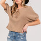 Model wearing SAGE+FIG lace-up waffle knit crop top with distressed shorts and a hat, showcasing trendy casual style.