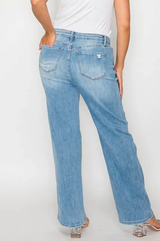 Woman showcasing distressed high rise straight jeans from the back, featuring a classic light blue wash and relaxed fit.