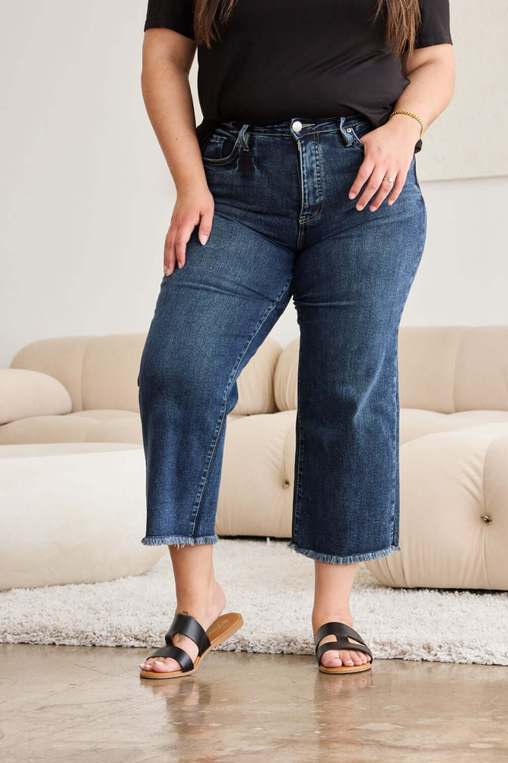 Woman wearing RFM Jeans Tummy Control High Waist Raw Hem Distressed Jeans in a living room setting.