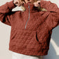 Quilted half zip long sleeve sweatshirt in rust, featuring a cozy pocketed design perfect for stylish comfort.