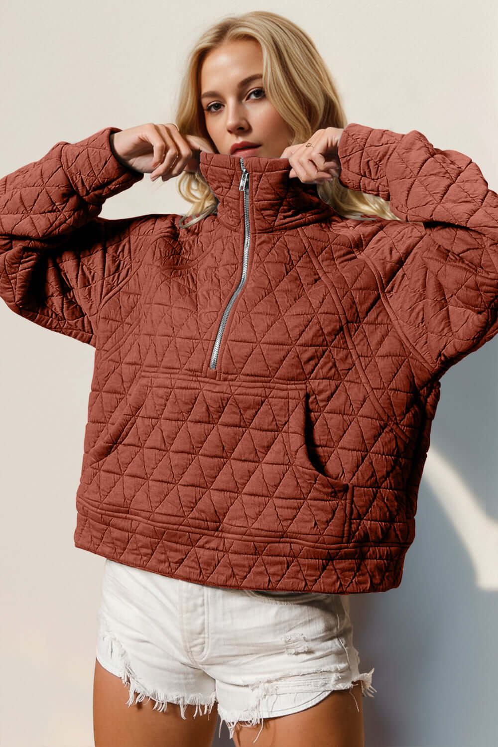 Quilted half zip long sleeve sweatshirt in rust, featuring a cozy pocketed design perfect for stylish comfort.