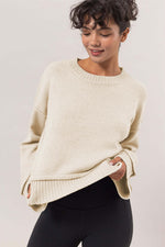 Chic model wearing a cream ribbed sweater with dropped shoulders, showcasing a relaxed style perfect for layering.