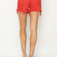 Bold red high rise distressed denim shorts by Risen Jeans, showcasing the trendy frayed hem from the back.