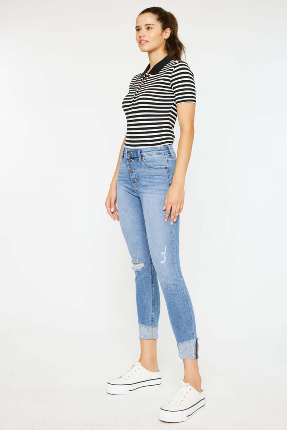 Woman wearing Distressed Cat's Whiskers Button Fly Jeans with a striped shirt and white sneakers, showing off casual and cool style