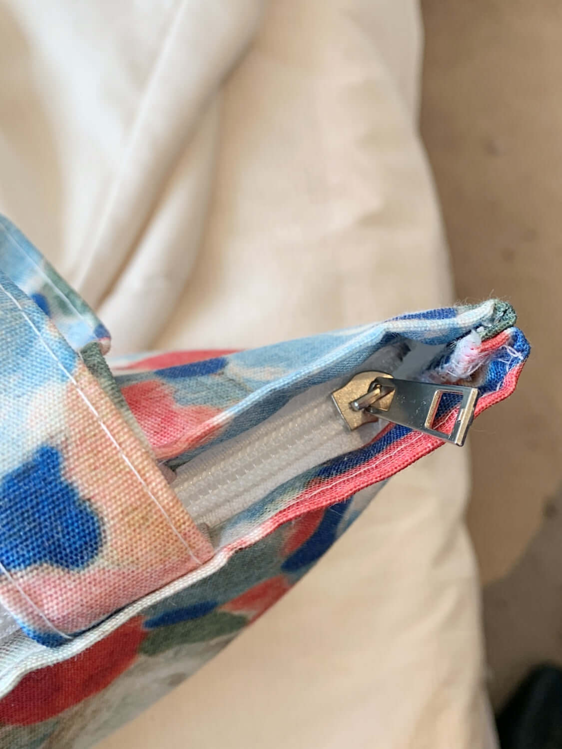 Close-up of a printed canvas handbag with a zipper, showcasing the detailed fabric pattern and sturdy zipper mechanism.