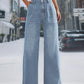 Woman wearing wide leg jeans with front pockets, buttoned design, slightly stretchy, 85% cotton, 15% polyester, background of urban street.