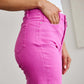 Woman wearing Crop Chloe Full Size Tummy Control High Waist Raw Hem Jeans in vibrant pink color.