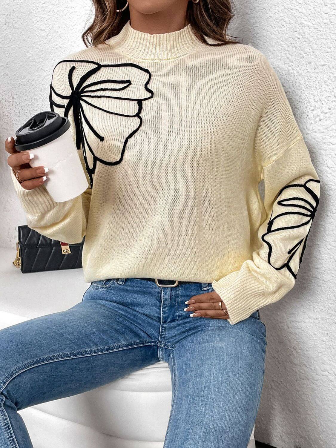 Woman wearing Perfee Mock Neck Dropped Shoulder Long Sleeve Sweater in light yellow with black butterfly design, holding coffee cup