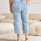 Woman wearing Tummy Control High Waist Raw Hem Distressed Jeans in petite size from RFM Jeans, showing back view and detailing