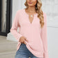 Woman wearing Bella Road Waffle-Knit Notched Long Sleeve T-Shirt in pink paired with blue jeans standing on steps