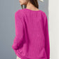 Woman wearing pink notched long sleeve T-shirt with thumbholes and white hat, viewed from the back. Casual and stylish look.