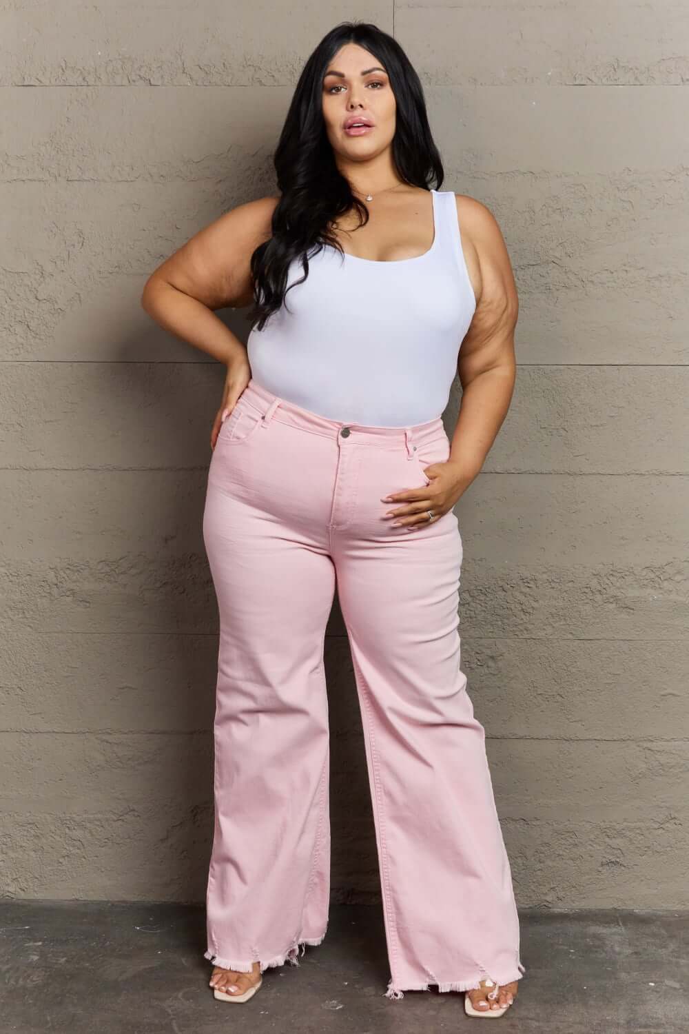 Woman wearing Raelene High Waist Wide Leg Jeans in Light Pink, showcasing Risen Jeans' chic and retro-inspired high-rise fashion.