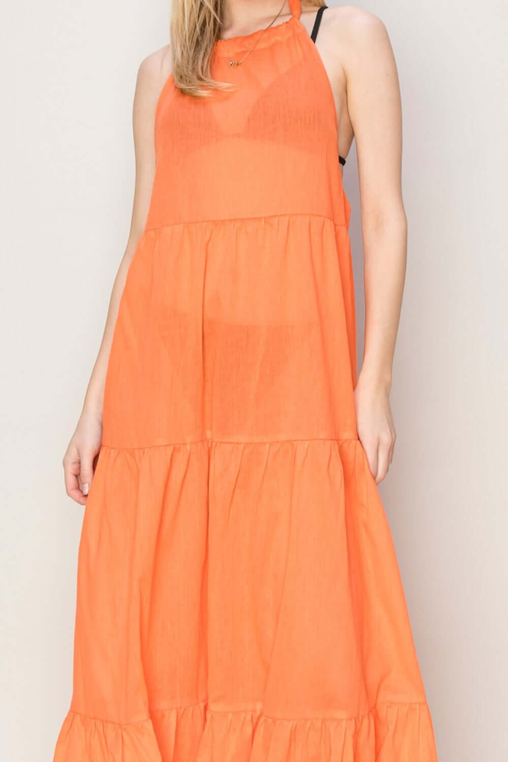 Halter neck orange maxi dress with loose-fit tiered silhouette, perfect for warm days and tropical getaways.