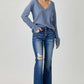 Woman wearing Risen Jeans distressed button-fly flare jeans with a blue sweater, showcasing stylish flair and comfort.