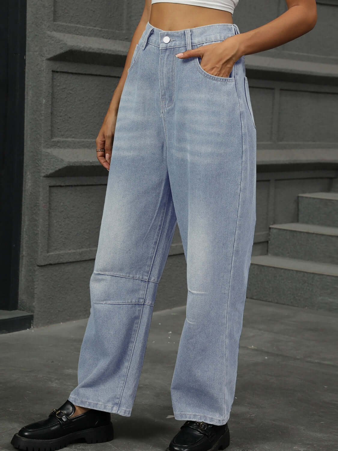 Woman wearing half elastic waist straight leg jeans in light blue with black shoes.