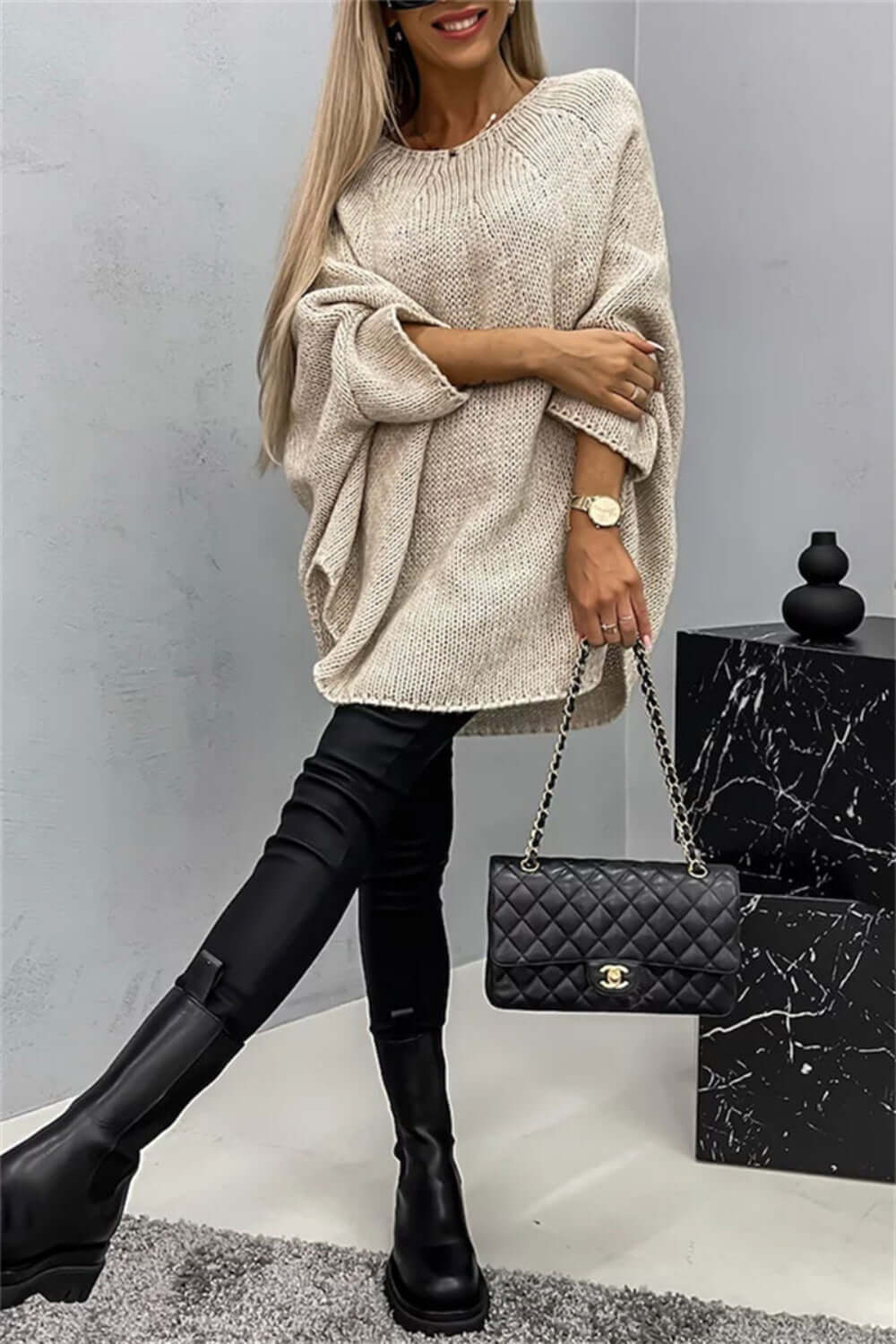 Woman in Bella Road Round Neck Batwing Sleeve Sweater, chic and cozy outfit with quilted black handbag.